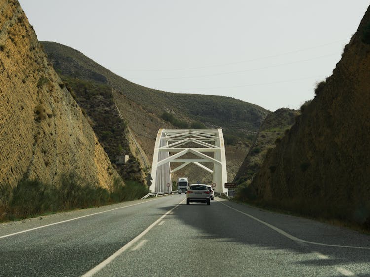 A Moving Cars On The Road Near The Mountain And Bridge