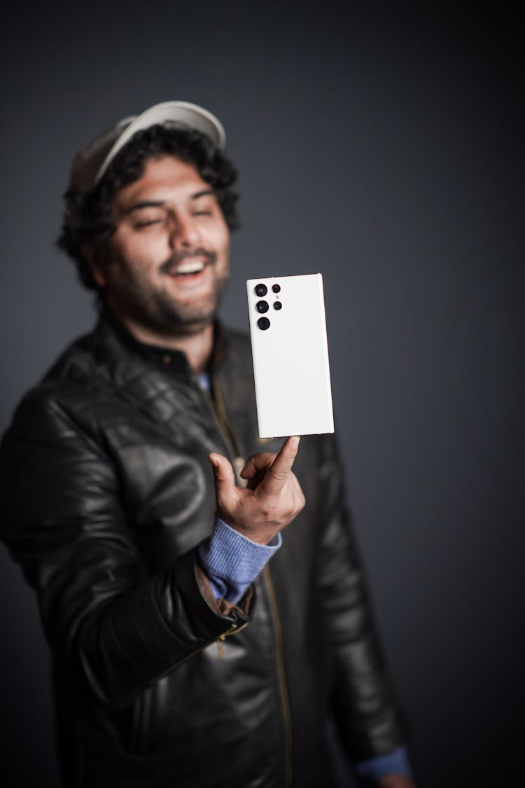 Man In Black Leather Jacket Balancing His Phone On His Finger