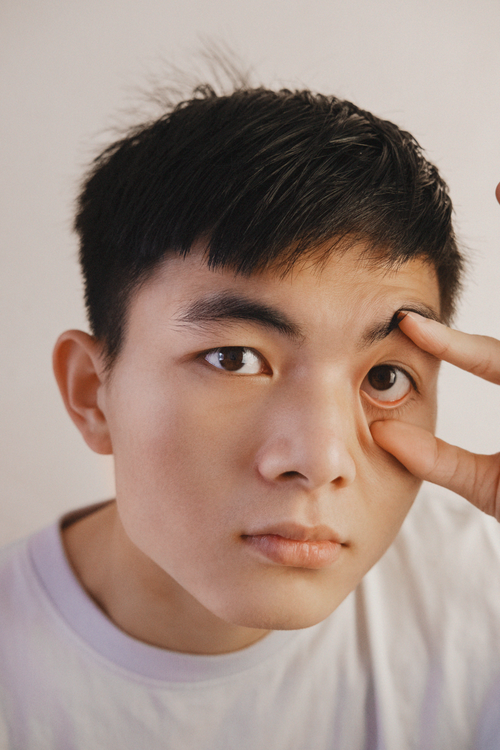 Free A detailed close-up of a young man examining his eye against a white background. Stock Photo