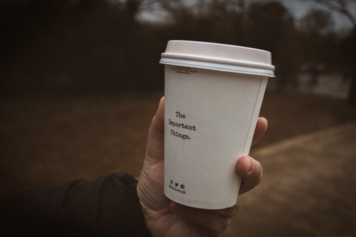Free A hand holds a coffee cup with a motivational quote outdoors in London. Stock Photo