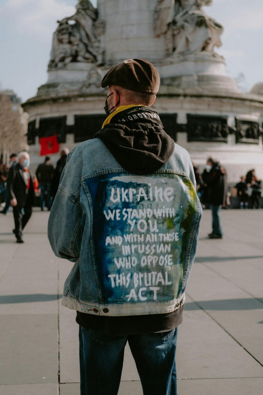 A man wears a jacket reading "Ukraine we stand with you and all those in Russia who oppose this brutal act."