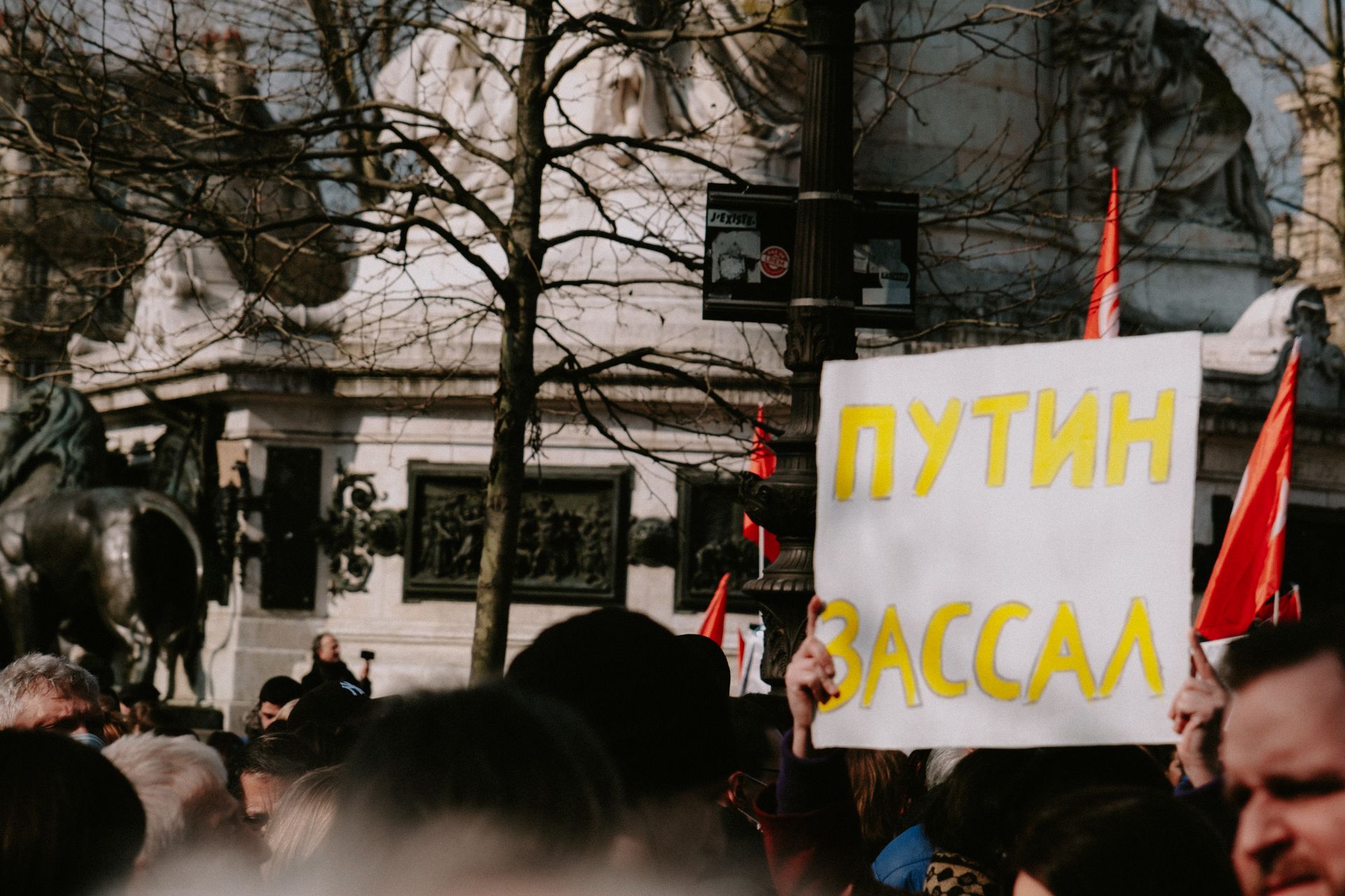 Crowd gathered at a protest holding a sign in an urban setting.