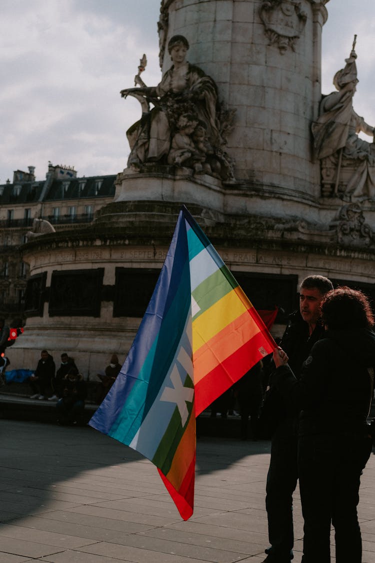 Couple With Rainbow Flag Standing At Monument