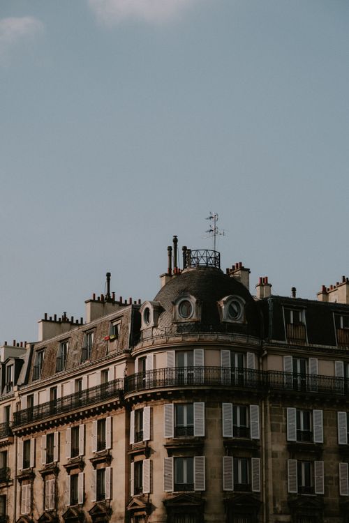 Free A classic Parisian building with ornate facade and window shutters under a clear blue sky. Stock Photo