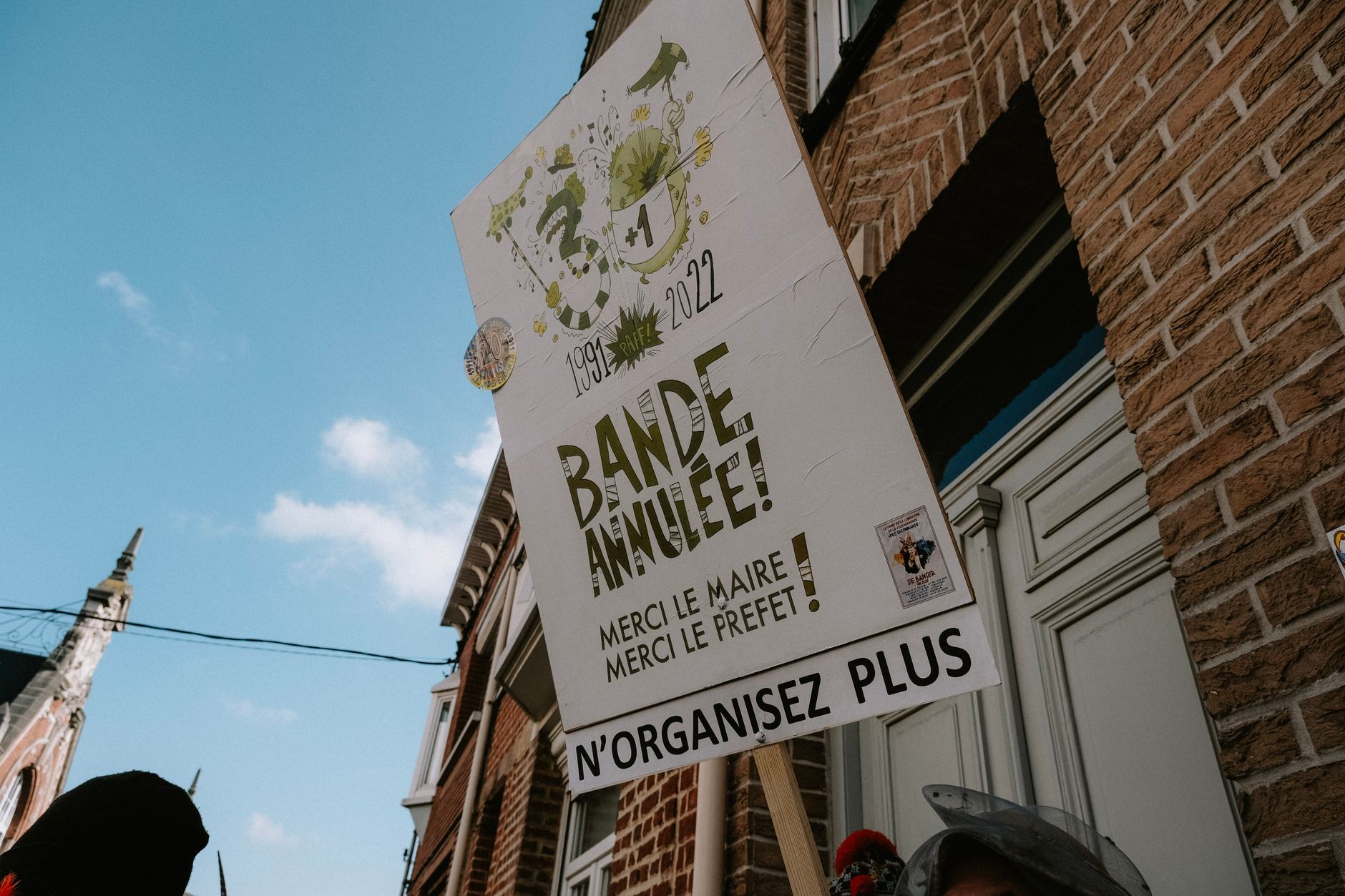 Street sign in front of a brick building under a clear sky, featuring text in French.
