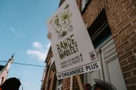 Street sign in front of a brick building under a clear sky, featuring text in French.