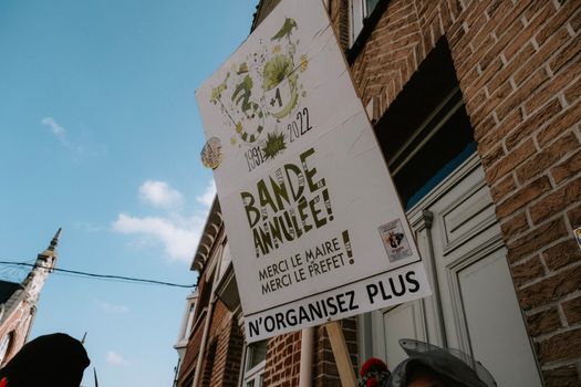 Street sign in front of a brick building under a clear sky, featuring text in French.