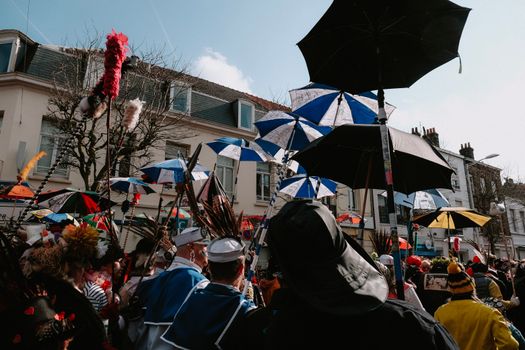 Vibrant street festival featuring umbrellas and costumes in a lively crowd.