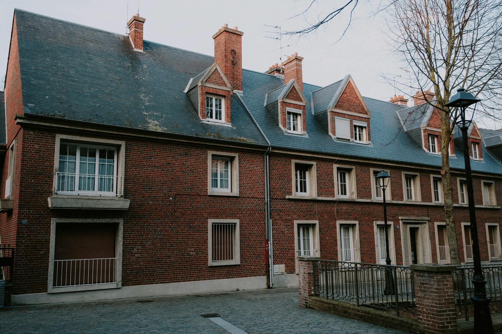 A classic brick building with dormer windows and chimneys under a tranquil sky.