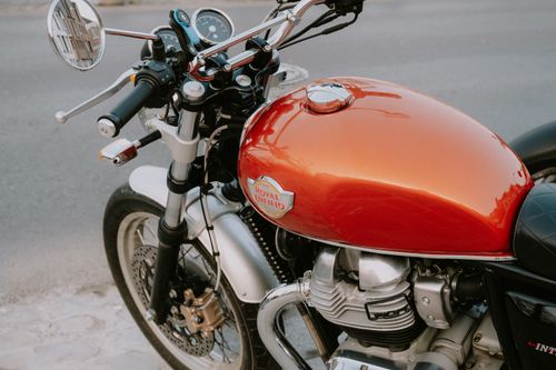 Free Detailed close-up of a Royal Enfield motorcycle tank with chrome accents on a street. Stock Photo