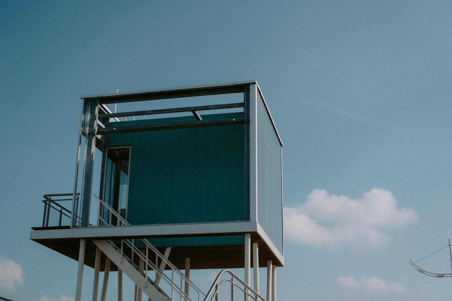 A minimalistic elevated house with a modern design set against a clear blue sky.