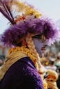 Man Wearing Purple and Yellow Outfit and Hat Made of Feathers