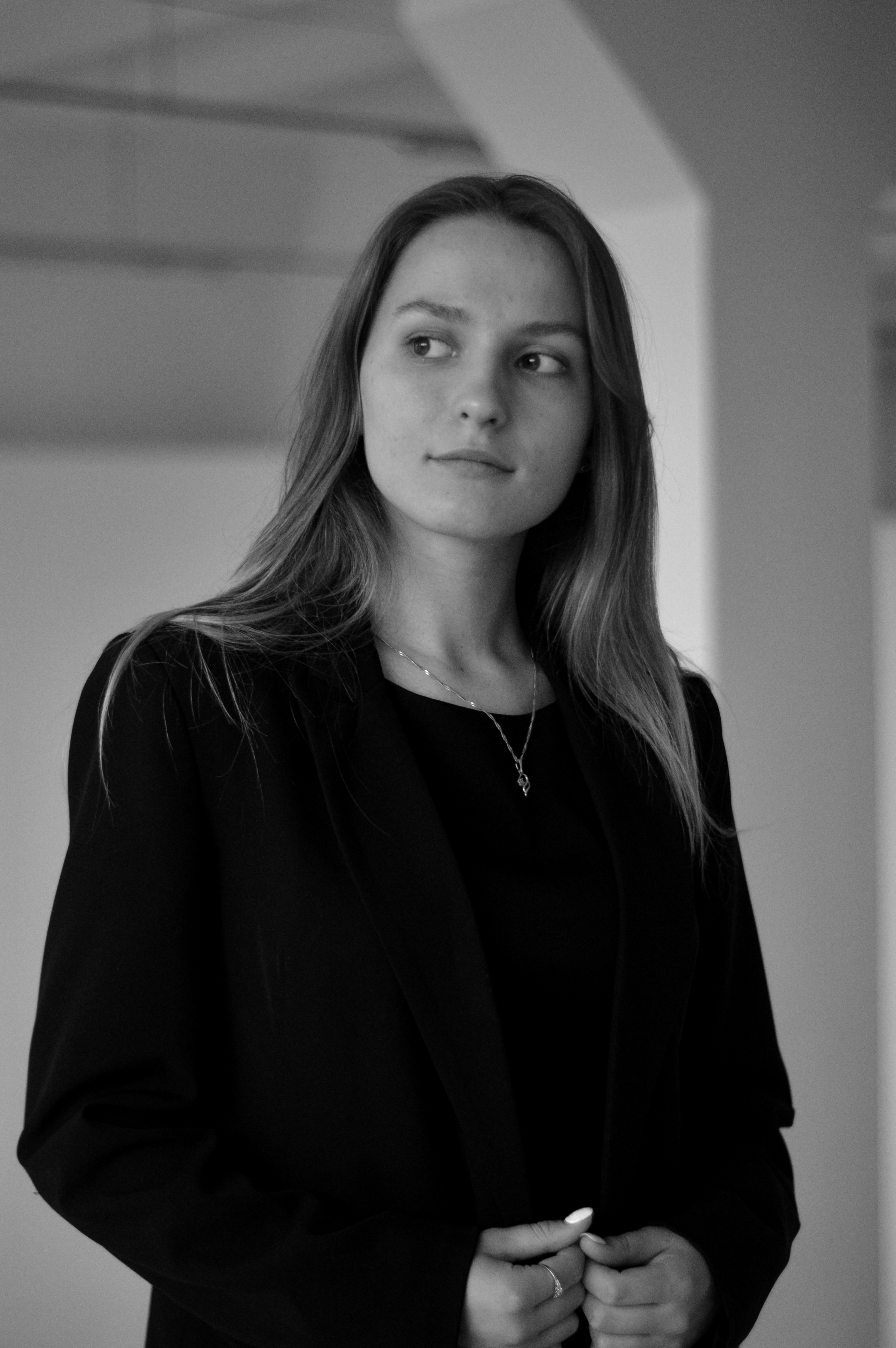 Black and white portrait of a woman in a formal outfit, looking contemplative.