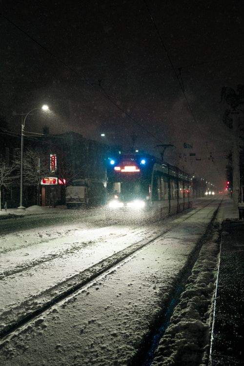 Free A streetcar moves through a snowy night in Toronto, illuminating the winter streetscape. Stock Photo
