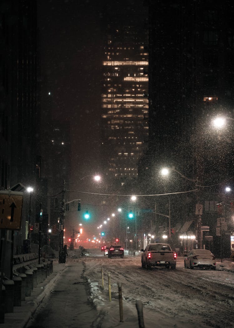 Cars Driving On Snowy Road At Night