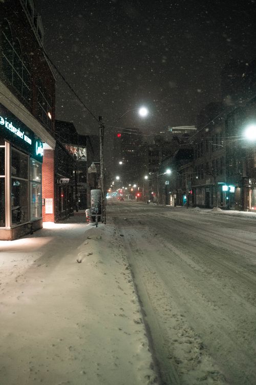 Free A serene winter night street view in Toronto, Canada, covered in snow and illuminated by streetlights. Stock Photo