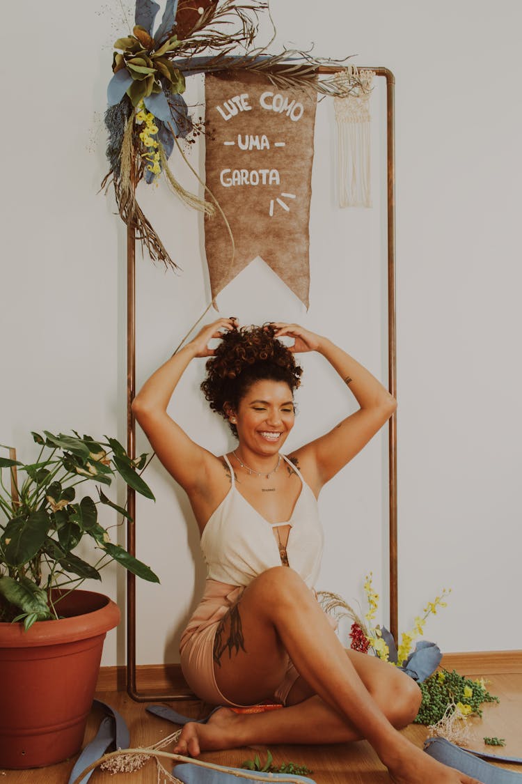 Woman Sitting On Messy Workshop Floor Laughing