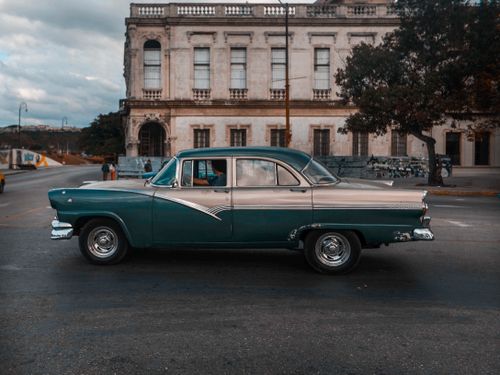 Free A classic vintage car on a city street with a historic building backdrop. Stock Photo