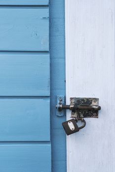 Weathered blue wooden door with a rusty padlock, symbolizing security and history.