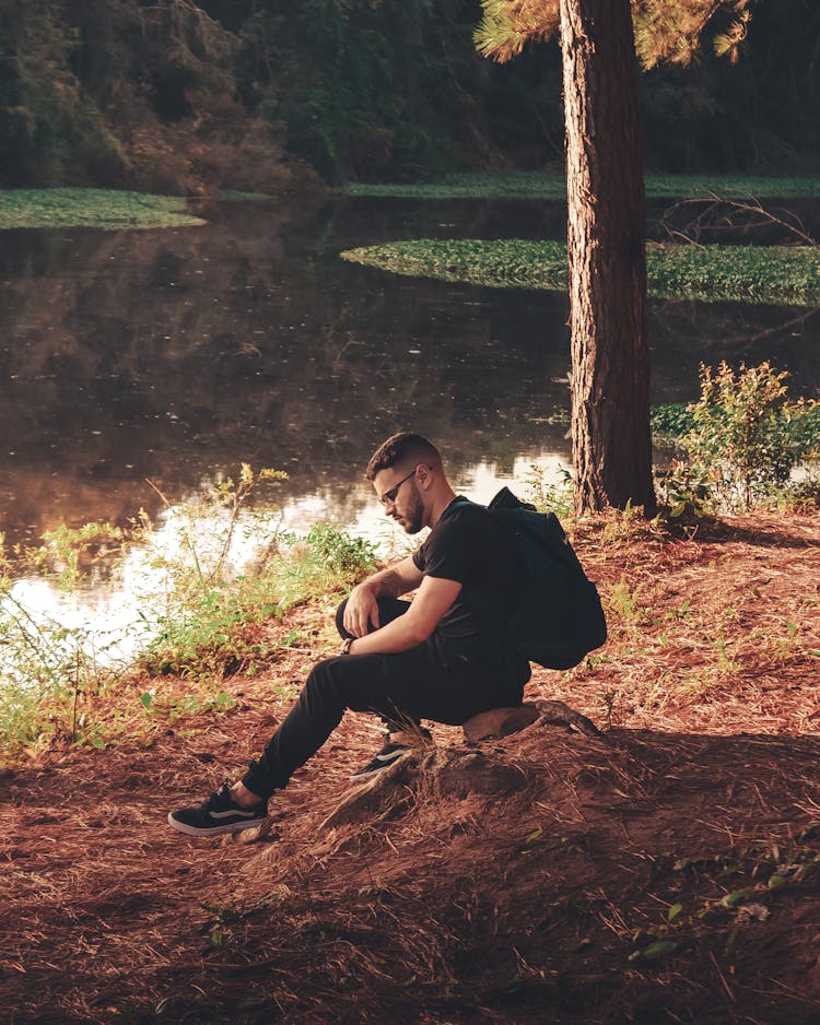 Man Sitting On River Bank In Park