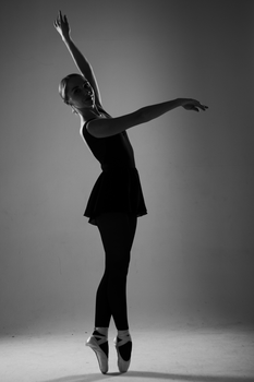 Elegant black and white portrait of a ballerina posing in a studio, showcasing poised ballet form.