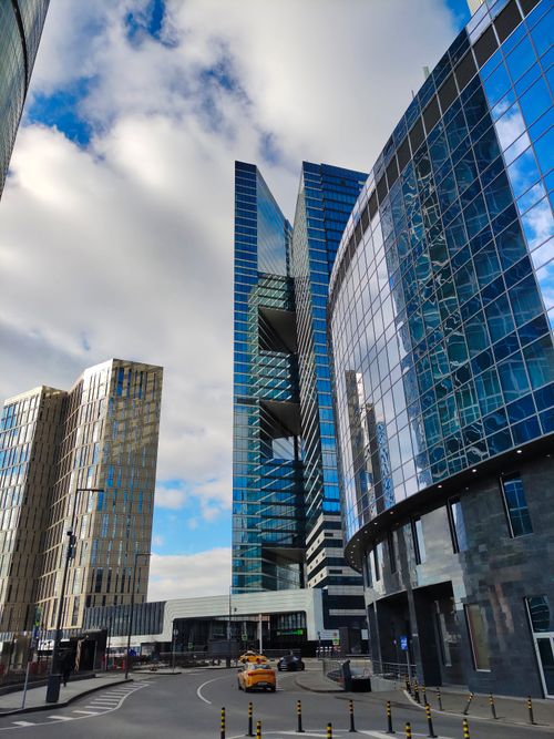 Free Contemporary skyscrapers with glass facades under a cloudy blue sky in a bustling cityscape. Stock Photo