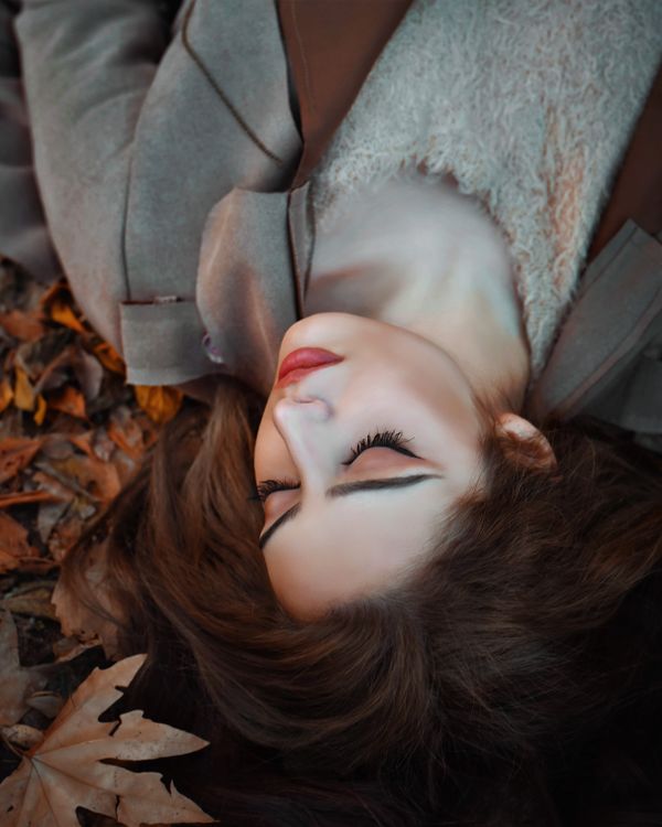 A Woman in Gray Long Sleeve Shirt Lying on Dried Leaves · Free Stock Photo