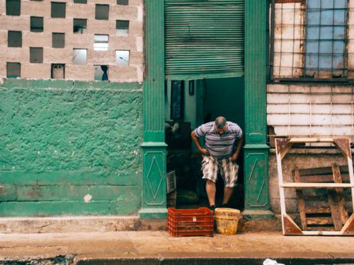 Free Man exits a green shop entrance on an urban street with unique architecture. Stock Photo