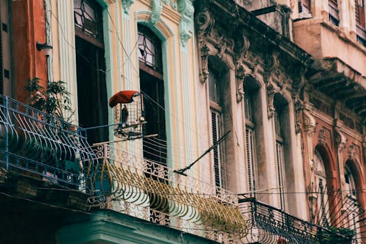 Photo of ornate old building facade featuring balconies and hanging bird cage in a cityscape.