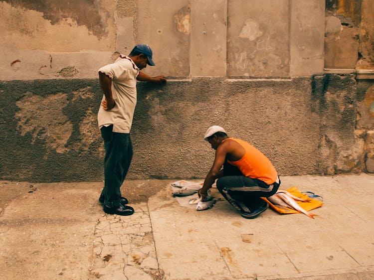 Man Gutting Fish On Pavement