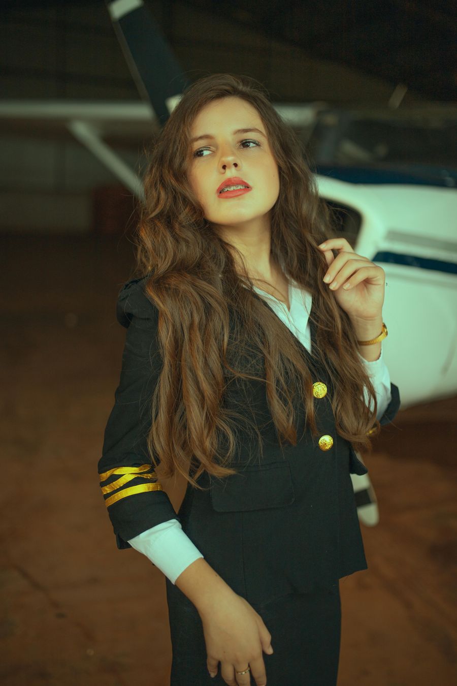 Confident female pilot in uniform inside aircraft hangar