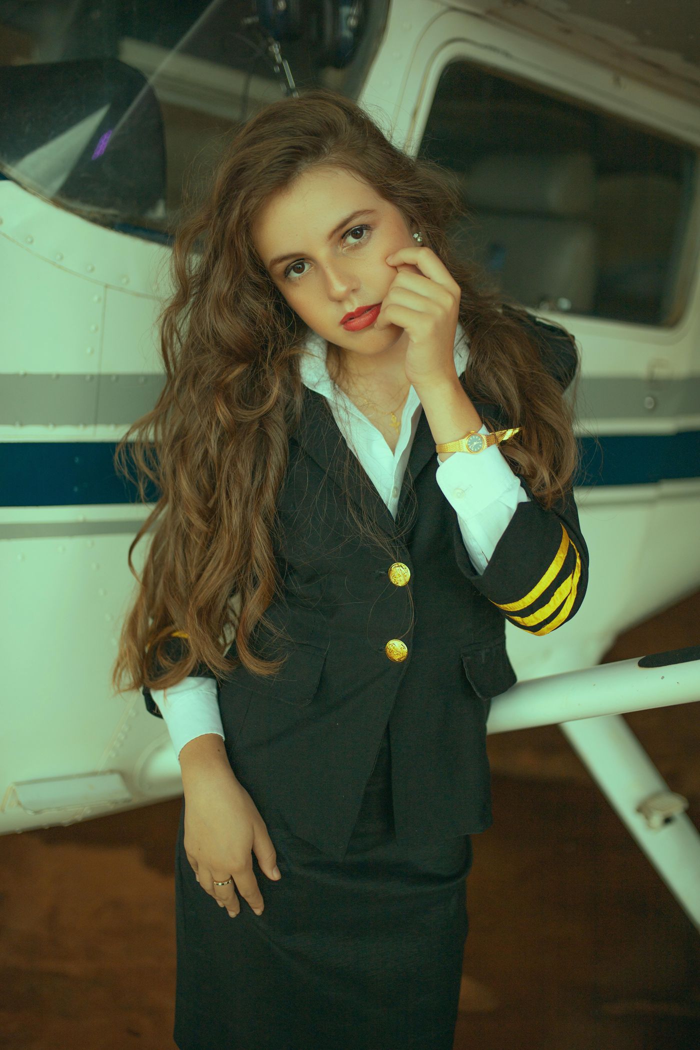 Female pilot in uniform standing beside small aircraft