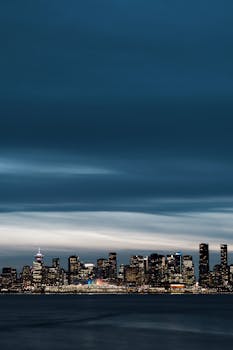 A stunning night view of Vancouver's cityscape under a deep blue sky, showcasing the illuminated skyline.