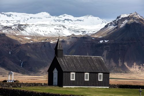 Free Black church against a dramatic mountainous backdrop in Vik, Iceland. Stock Photo