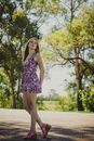 Woman in White Pink and Blue Floral Sleeveless Dress Standing on Gray Concrete Road