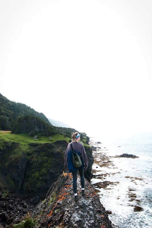 Hiker on a grassy coastal cliff above the sea, photo by Britt Pigat on Pexels