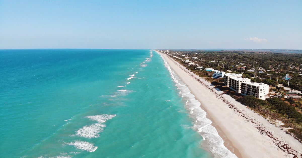 A stunning aerial image capturing a pristine beach coastline with turquoise water.