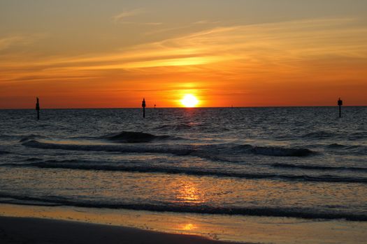 A captivating sunset over the ocean with calm waves and vibrant orange hues creating a tranquil scene.