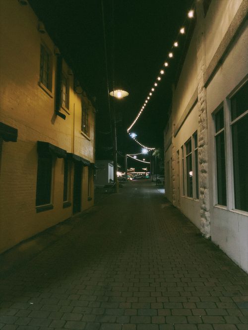 Free A cozy and well-lit brick alleyway in Florida, showcasing urban charm and evening ambiance. Stock Photo