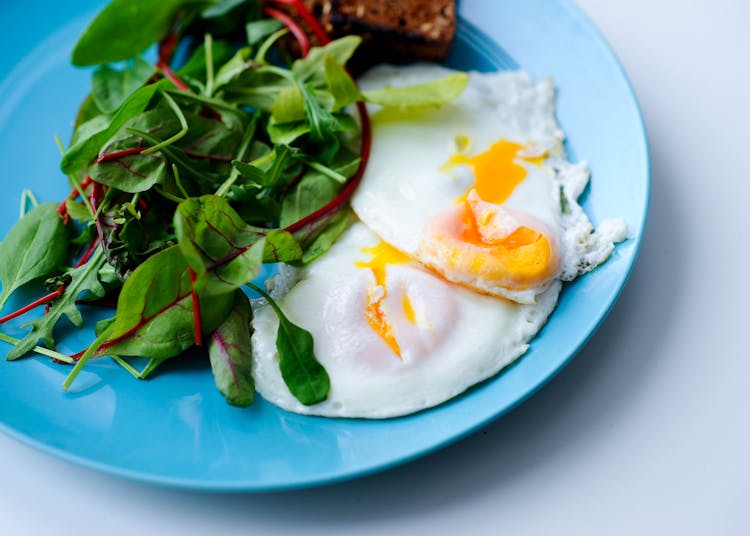 Cooked Eggs And Spinach On Blue Plate