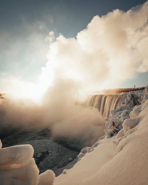 Breathtaking winter scene of a frozen Niagara Falls with cascading mist.