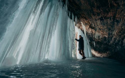 Free A man stands inside a stunning ice cave adorned with large icicles, exploring its natural beauty. Stock Photo