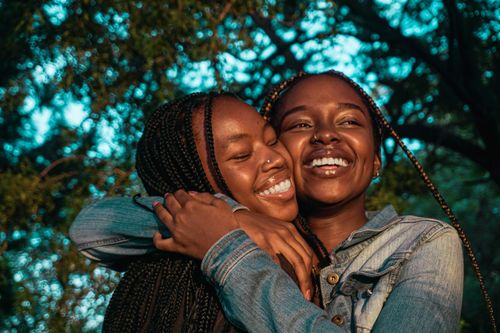 Free Two joyful African women with braids hugging and smiling outdoors in Botswana. Stock Photo