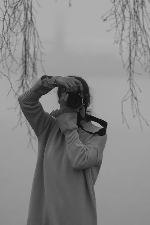 Grayscale Photo of a Woman Taking Photo with a Camera