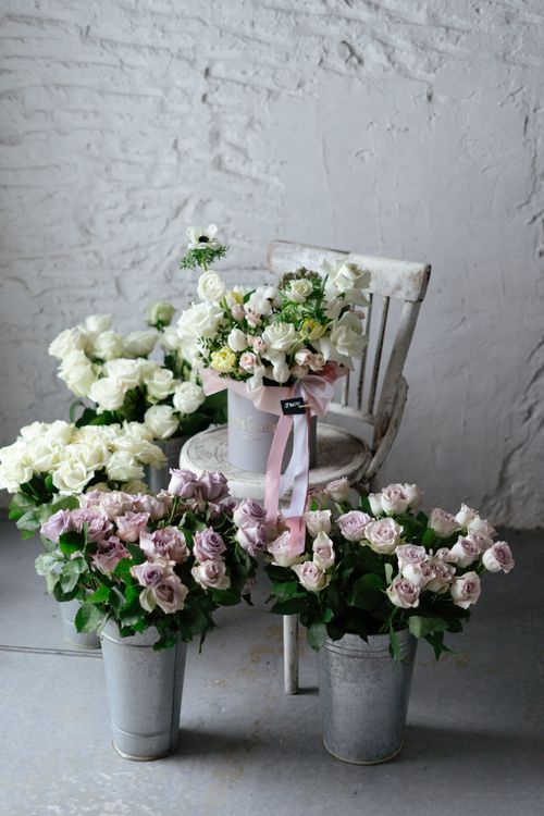 Free White roses and pastel flowers in metal buckets and a vintage chair indoors. Stock Photo