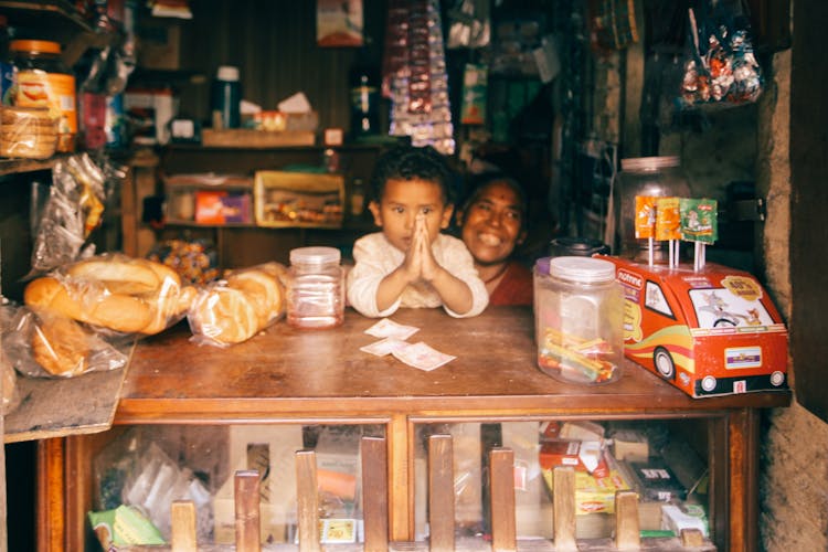 Little Kid Sitting At Street Shop Counter 