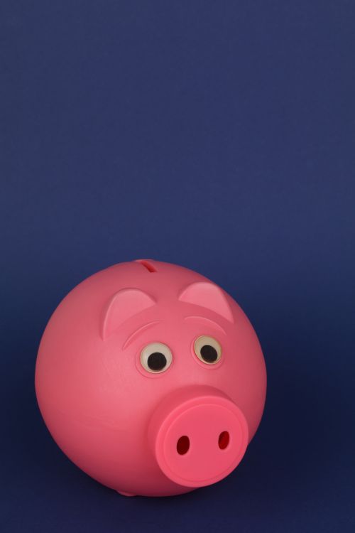 Free Close-up of a pink piggy bank with a dark blue background, symbolizing savings and finance. Stock Photo
