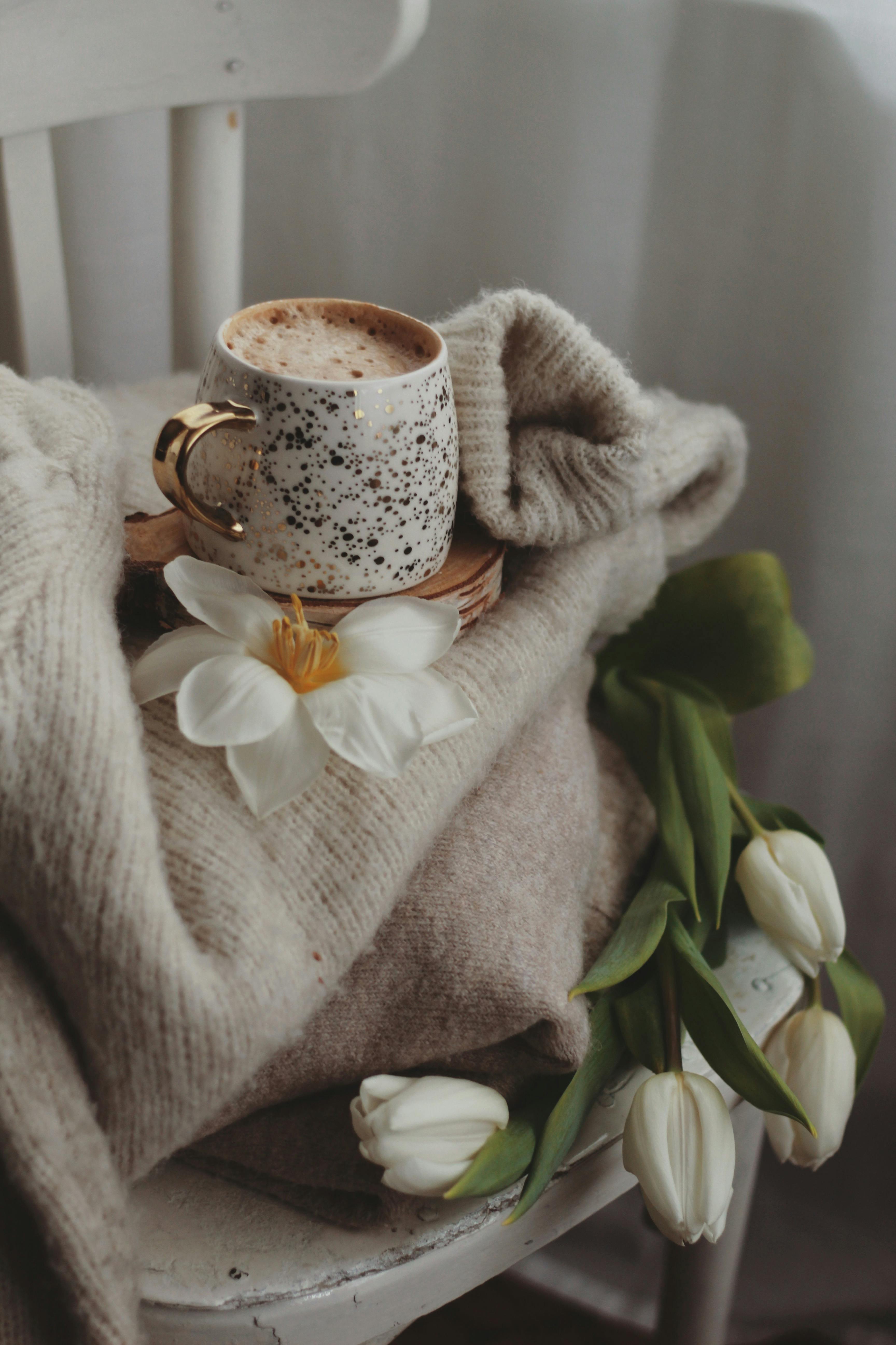 cup of milky coffee standing on wooden pad on chair