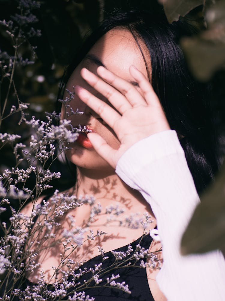 Woman Holding Wildflowers Covering Face With Hand