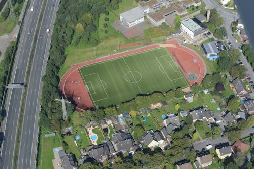 Foto profissional grátis de aerofotografia, campo de futebol, casas